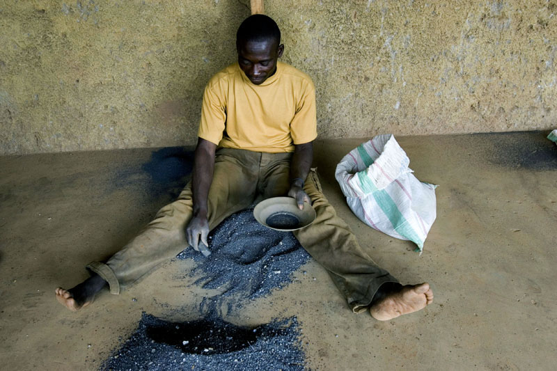 Coltan worker / A man works over a coltan mound, separating residues off the mineral, Bukavu, DR Congo